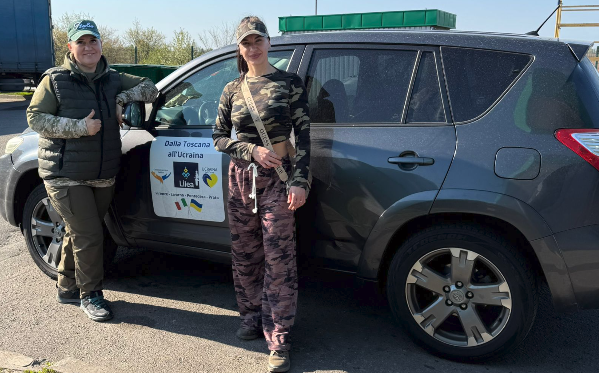 Two Ukrainian soldiers posing in front of a donated SUV