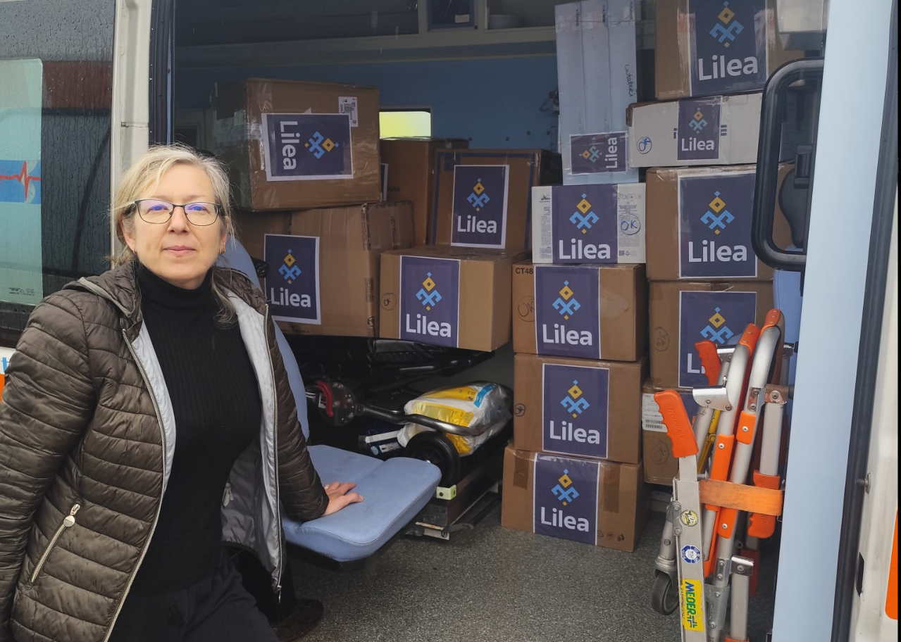 Oksana from Lilea, posing next to a truck loadead with Lilea branded medical supply boxes